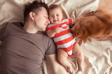 Father with baby son and pet Shiba Inu Dog having fun and playing at home, top view.