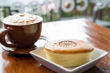 Japanese cheese cake in white plate on wooden desk and brown cup of coffee in the background