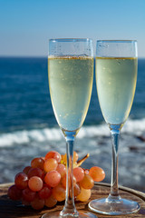 Champagne, prosecco or cava served with pink grape in two glasses on outside terrace with sea view