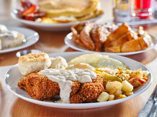 chicken fried steak covered in gravy with sunny side up eggs and breakfast foods at restaurant