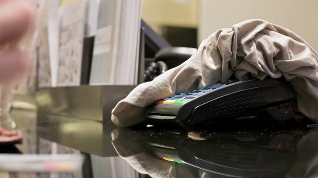 Card reader to pay by credit card covered with purchased clothes. Female hand in defocus holds a card for payment at the ready in the store. Banking services of electronic money. Use debit card