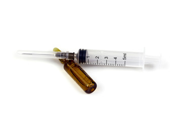Brown transparent drug ampoule and white 5ml medical syringe lie on the white background. The concept of vaccination, injection and medical procedures.