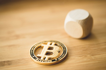One golden bitcoin next to a wooden cube