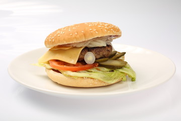 cheeseburger with beef cutlet, bacon, tomatoes and cheese slices, seasoned with sauce and green salad for a restaurant menu on a white isolated background