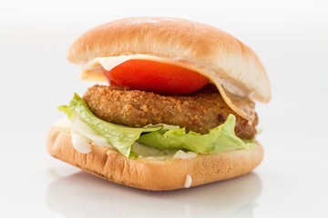 cheeseburger with beef cutlet, bacon, tomatoes and cheese slices, seasoned with sauce and green salad for a restaurant menu on a white isolated background