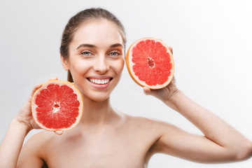 Healthy topless woman standing isolated over white background showing sliced grapefruit