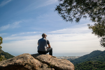 Fototapeta na wymiar Hiker sitting on a rock with great view, back view