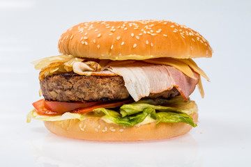 cheeseburger with beef cutlet, bacon, tomatoes and cheese slices, seasoned with sauce and green salad for a restaurant menu on a white isolated background