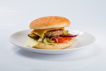 cheeseburger with beef cutlet, bacon, tomatoes and cheese slices, seasoned with sauce and green salad for a restaurant menu on a white isolated background