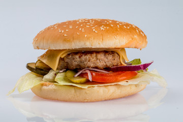 cheeseburger with beef cutlet, bacon, tomatoes and cheese slices, seasoned with sauce and green salad for a restaurant menu on a white isolated background