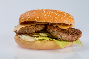 cheeseburger with beef cutlet, bacon, tomatoes and cheese slices, seasoned with sauce and green salad for a restaurant menu on a white isolated background