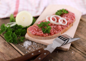 slice of bread with minced meat, parsley and onions - on rustic wooden table - breakfast bread - pork mett