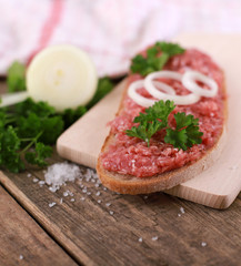 slice of bread with minced meat, parsley and onions - on rustic wooden table - breakfast bread - pork mett