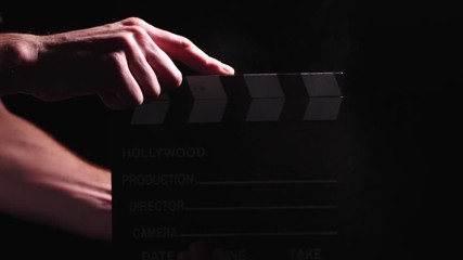 Hollywood production clapperboard clacking with powder dust in a low light setting
(close up shot)