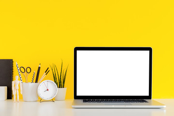 Desk and laptop isolated on a yellow background office workspace. Mock up.	