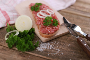 slice of bread with minced meat, parsley and onions - on rustic wooden table - breakfast bread - pork mett