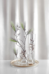 Scandinavian Easter interior decoration. Spring branch with plumets in glass vases on the brass tray.