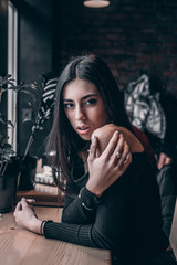 cute girl with silver jewelry sits in a loft style cafe