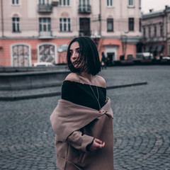 Fototapeta premium cute brunette in a coat walks around the city