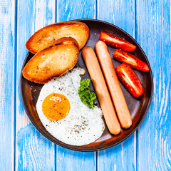 English breakfast - fried egg, sausages, toasts and vegetables