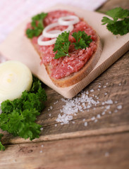 slice of bread with minced meat, parsley and onions - on rustic wooden table - breakfast bread - pork mett