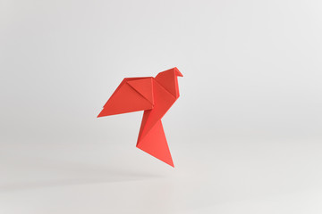Origami dove made of red paper on white background. Minimal concept.
