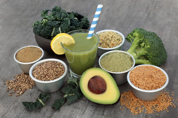 Healthy juice smoothie drink with hemp and matcha powder, flax, hemp husks and seeds with fresh green vegetables on rustic wood background. High in omega 3, antioxidants, vitamins and dietary fibre.