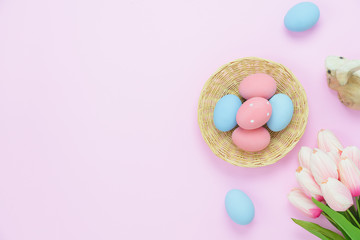 Table top view shot of decorations Happy Easter holiday background concept.Flat lay arrangement bunny eggs in wooden basket & with tulip on modern rustic pink paper.Copy space for creative design text