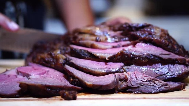 Slices of roast beef with hands carving meat in background, Slowmo Slider Shot