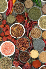 Herb and spice food selection dried and fresh on rustic wood background. With dried ring of fire, padron and scorpio chilli peppers. Top view.