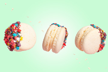White French Macaroons, Sweet and colorful French macaroons are falling or flying in motion. On a green background, with particles in motion