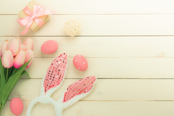 Table top view shot of decorations Happy Easter holiday background concept.Flat lay bunny eggs with pink tulip and variety decor for season and gift on modern rustic white wooden.Blank space design.