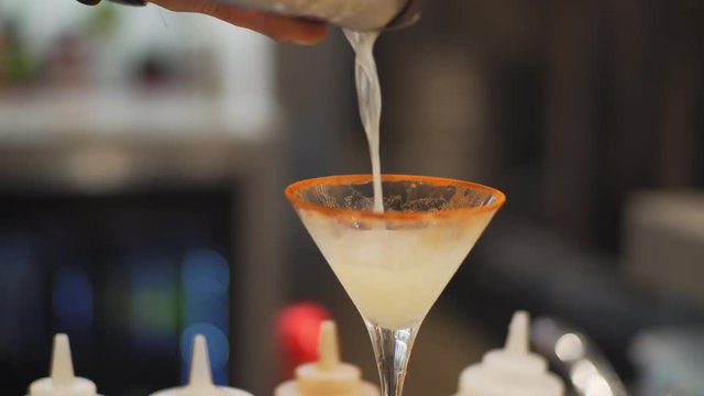 Autumn cocktail being poured from a shaker into a martini glass rimmed with cinnamon