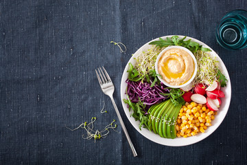 vegan avocado sweet corn lunch bowl with hummus, red cabbage, radish and sprouts