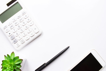 Top view of calculator, phone, tree and pen on white background with copy space in business concept.