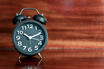 Black Alarm clock on wooden floor.