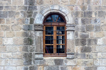 Fototapeta na wymiar The background old beige stony wall with a window