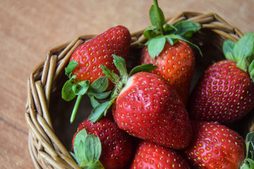 ripe red strawberries in a wicker basket in the form of a heart in the hands