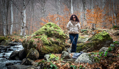 Woman stands by the small river in the forest. End of winter and beginning of the spring