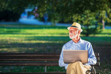 Senior man using laptop computer at rest in the park outdoors