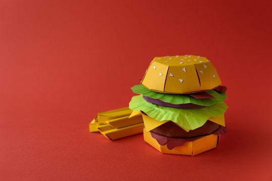 Naklejki Paper cheeseburger with beef, cheese, tomato, lettuce, onion, bacon and fries on red background. Copy space. Creative or art food concept