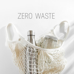 Cotton net bag with reusable metal water bottle, glass jar and straw. Zero waste concept. Eco...