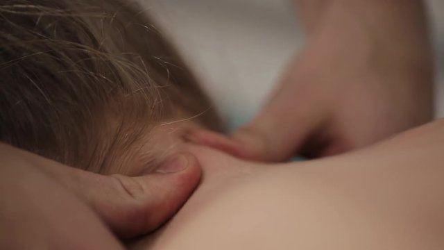 Little girl's head being manipulated by an osteopath, close up. Alternative medicine treatment. A professional masseuse does a neck massage for a girl in the spa centre