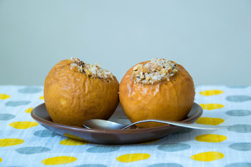 Baked Stuffed Apples on a Brown Saucer. Tablecloth in gray and yellow large peas.