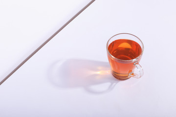 Glass cup with tea, on a white background. The harsh shade of the sun, the art concept of the...