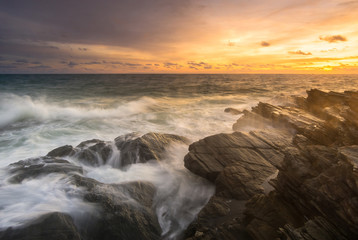 Beautiful natural seascape wave moving on the rock during sunrise