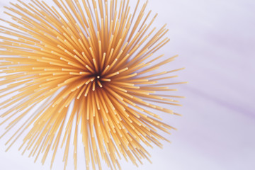 Beautiful raw spaghetti pasta. Spaghetti bunch on light background. Closeup shot, top view.