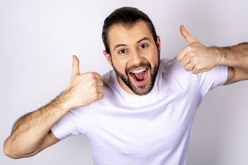 Handsome man in white t-shirt over white background looking at the camera and showing likes