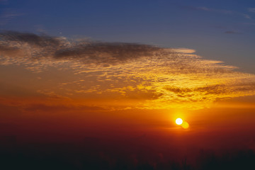 Sunny shine on clouds. Wonderful vivid dawn. Beautiful calm orange sunset. Scenic surreal sunrise. Amazing red blue cloudy sky. Picturesque sundown. Atmospheric cloudscape. Circle of sun above horizon