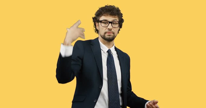 Angry attractive businessman in the glasses, suit and tie throwing documents away on the yellow wall screen.